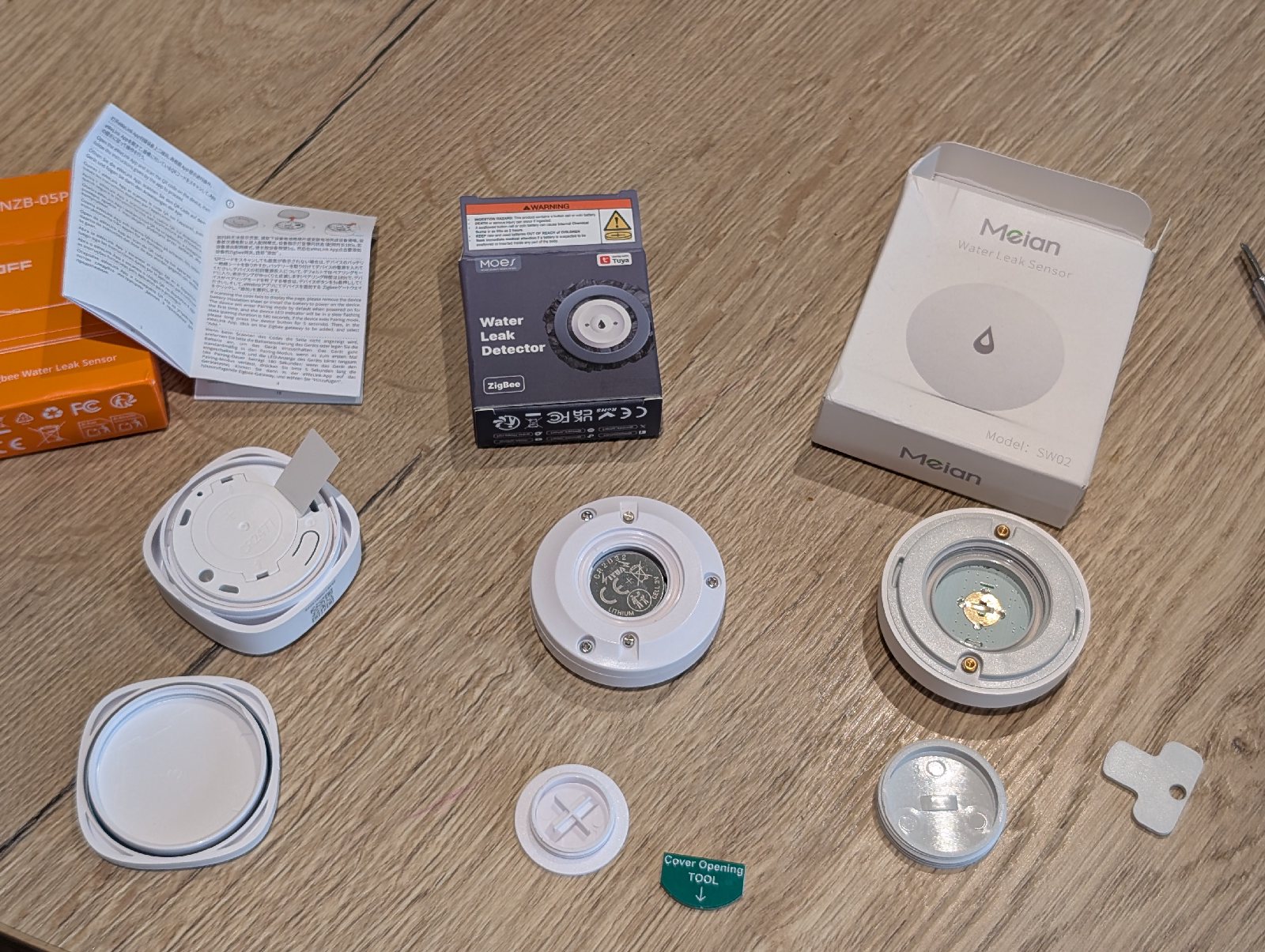 The Sonoff, Moes, and Meian leak sensors opened up to show their battery compartments