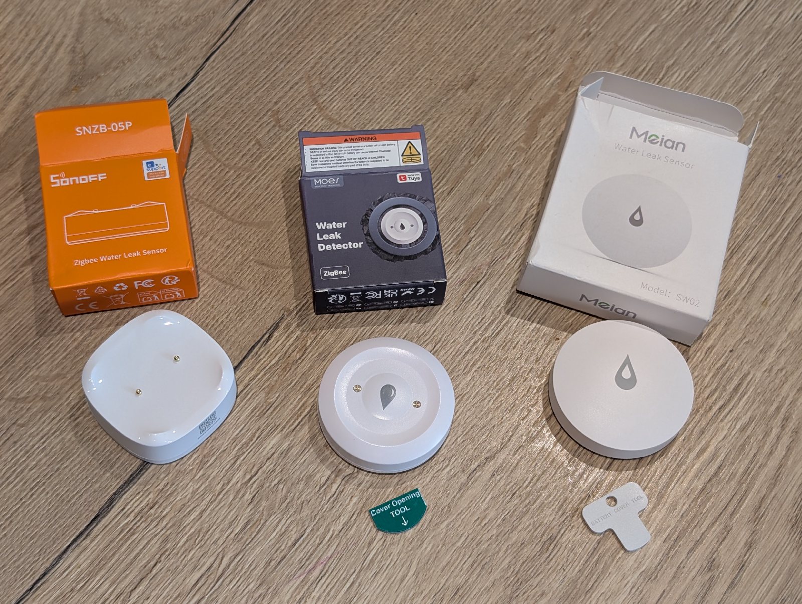 The fronts of the Sonoff, Moes, and Meian leak sensors laid out side by side